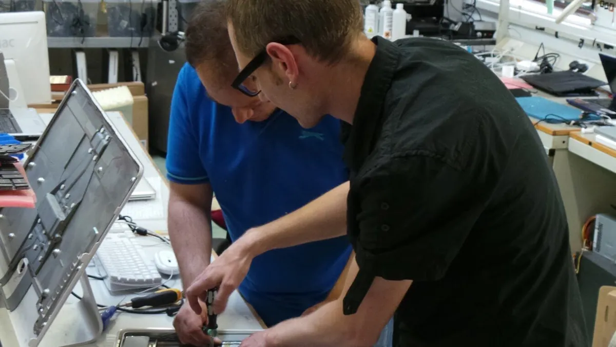 Two engineers working on laptops at the repair bench